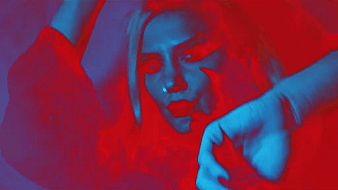 Photo of Ductape bandmember Çağla Güleray bathed in black/red light from music video Kara Buyu.